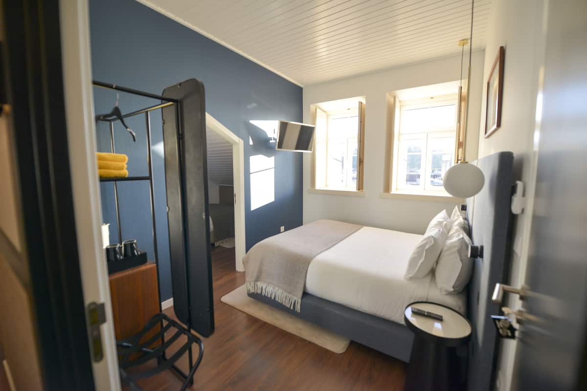 Un dormitorio con cama, mesita de noche y espejo.