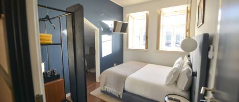 Un dormitorio con cama, mesita de noche y espejo.