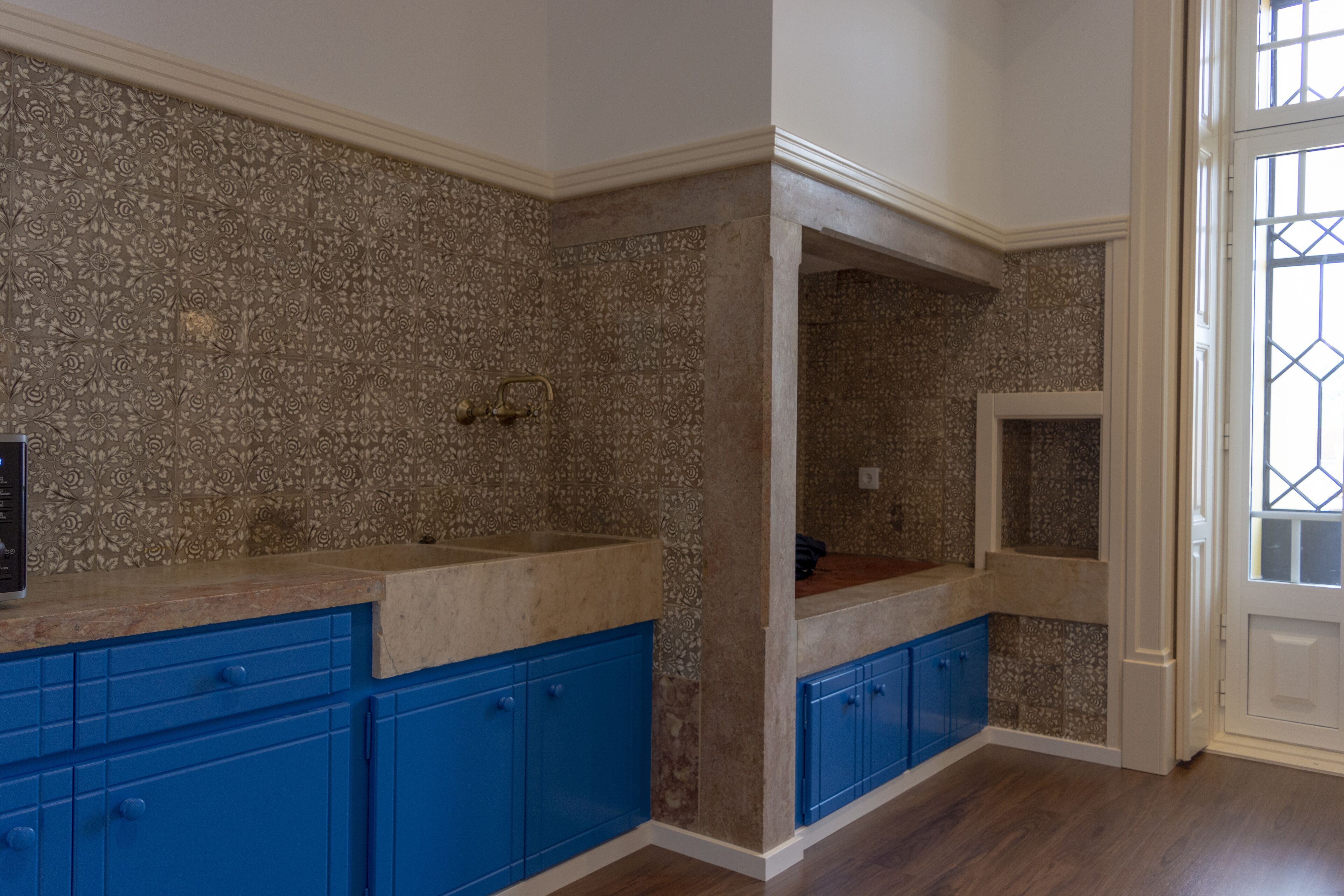 A kitchen with blue cabinets, a patterned backsplash, and a wooden countertop.