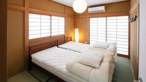 A traditional Japanese-style bedroom with two beds, large windows, and a hanging lamp. - Wave House 99 (Kujukuri)