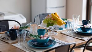 A dining table set with blue plates, clear glasses, and a fruit centerpiece. - Wave House 99 (Kujukuri)