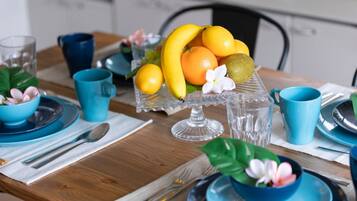 Une table à manger dressée avec de la vaisselle bleue, un centre de table composé de fruits et une tasse bleue.