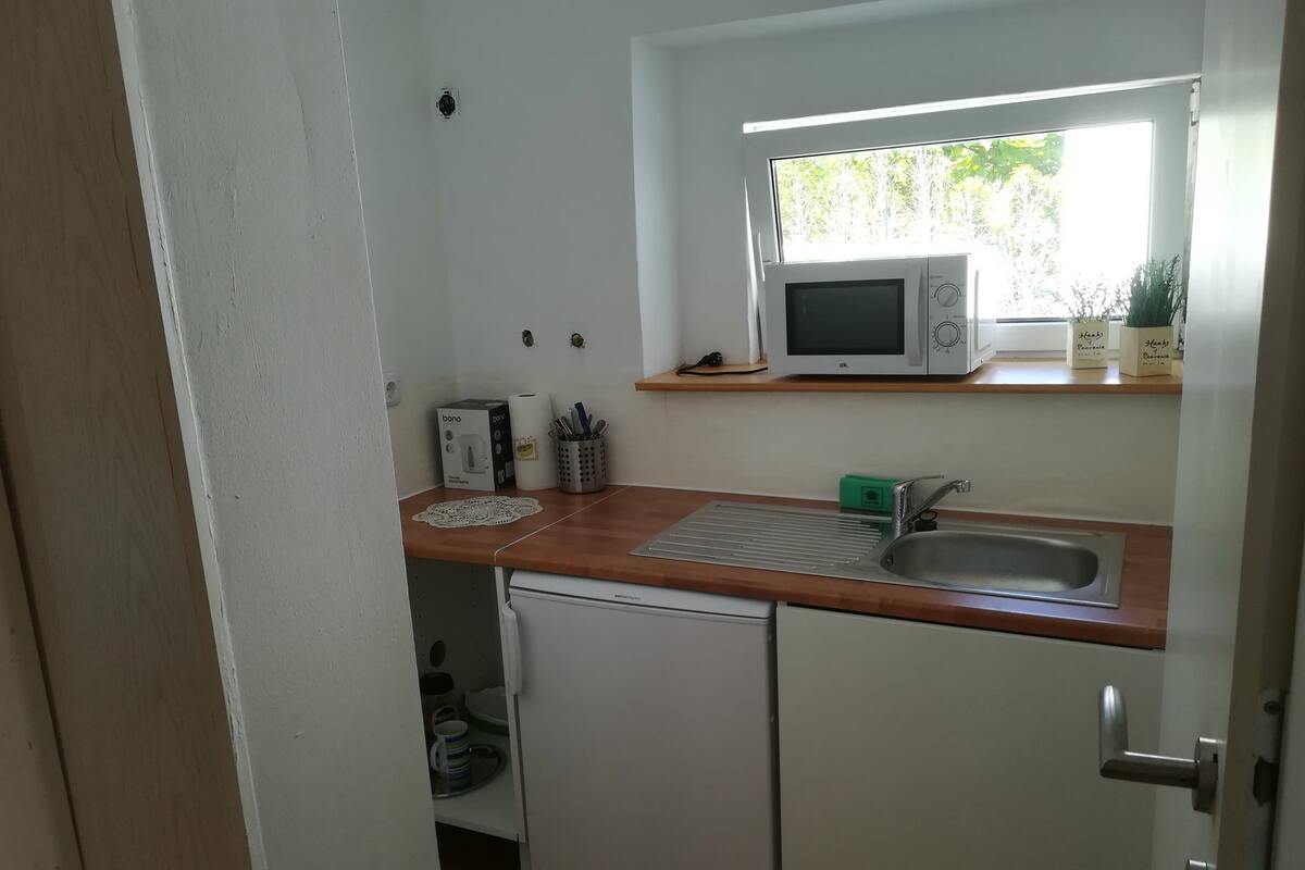 A compact kitchen with a microwave, sink, and small refrigerator.