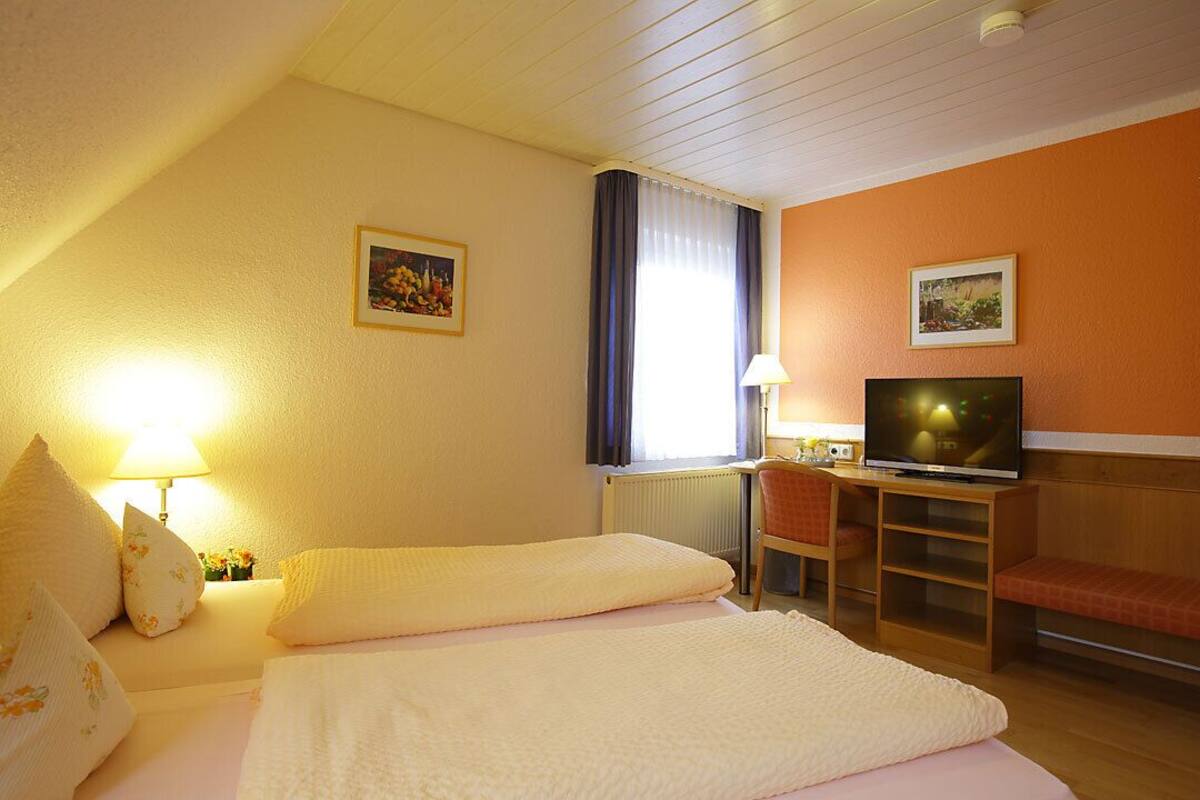 A hotel room with a bed, a television, a desk, and a chair.