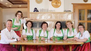 A group of people seated at a wooden table in a room with a tiled backsplash and a wooden door. - Hotel-Restaurant Gasthof Adler (Neuenburg am Rhein)