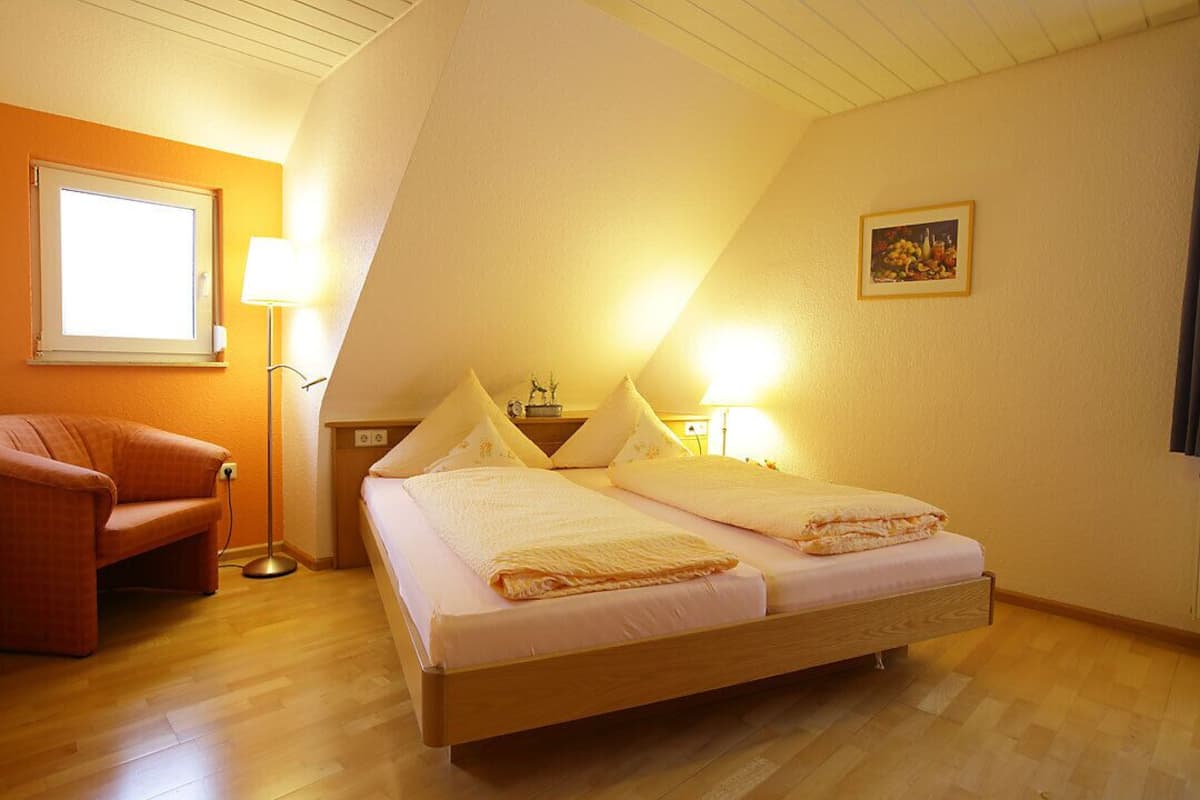 A bedroom with a wooden bed, two bedside tables, a floor lamp, and a chair.