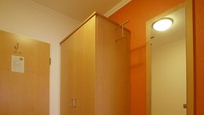 A hotel room with a wooden wardrobe, a bench, a mirror, and a tiled floor. - Hotel-Restaurant Gasthof Adler (Neuenburg am Rhein)