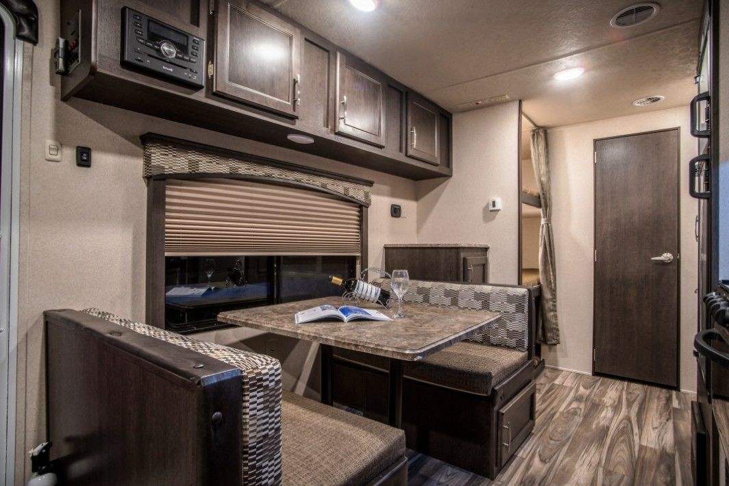 A compact RV kitchen with a built-in table, seating, and a microwave.