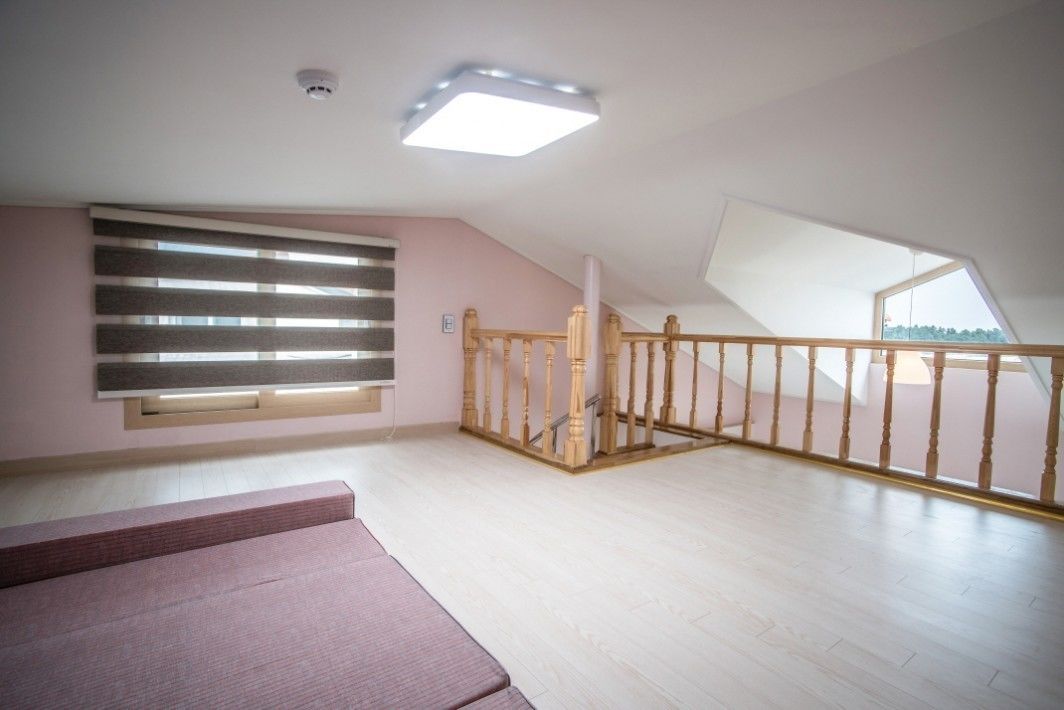 A spacious attic room with a sloped ceiling, a wooden staircase, and a large skylight.