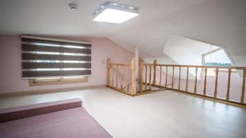 A spacious attic room with a sloped ceiling, a wooden staircase, and a large skylight.