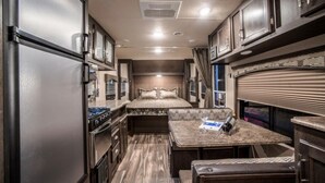 A compact RV interior with a kitchenette, a dining area, and a sleeping berth. - Oakra Resort (Seogwipo)