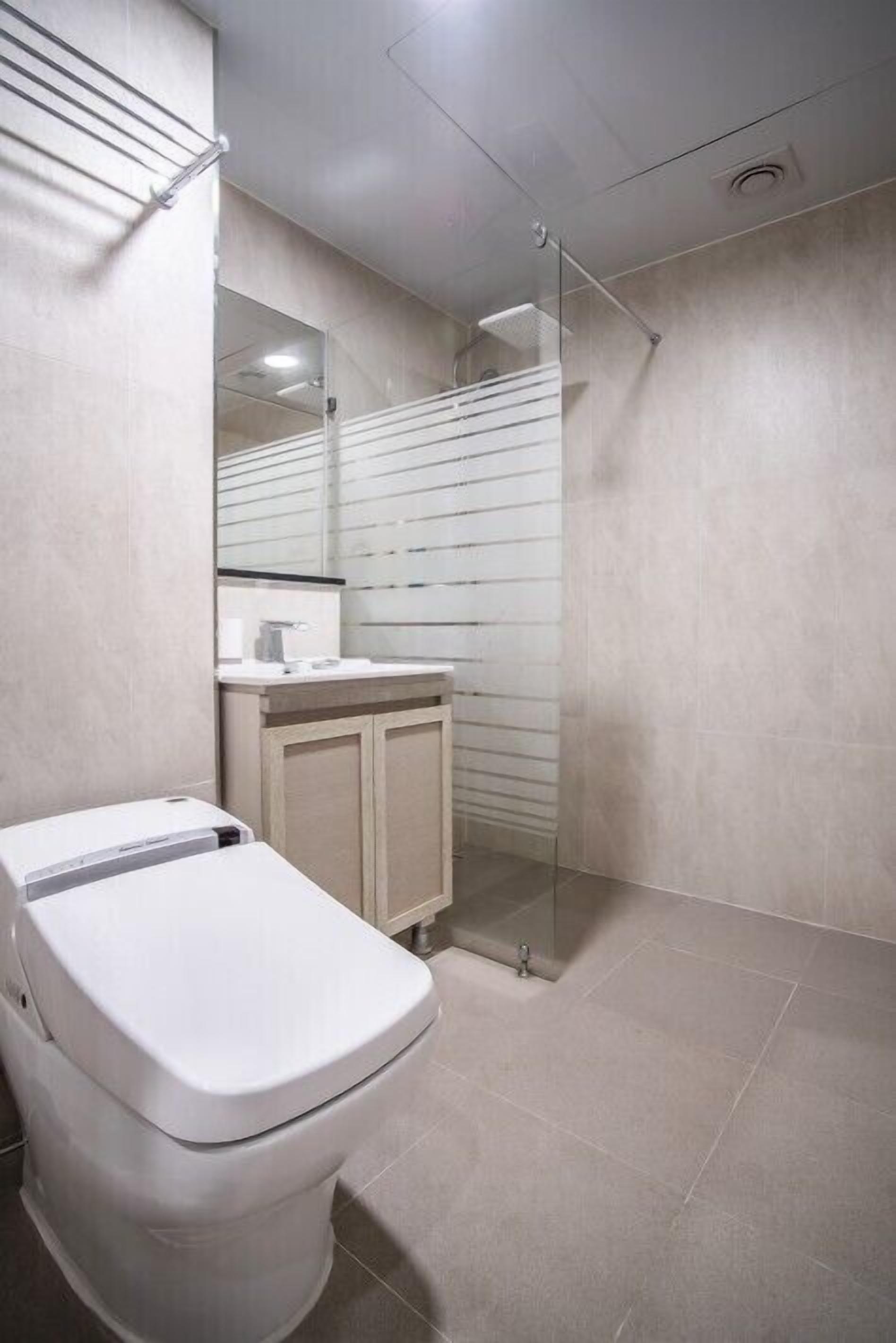 Un baño moderno con inodoro, lavamanos y cabina de ducha de vidrio.