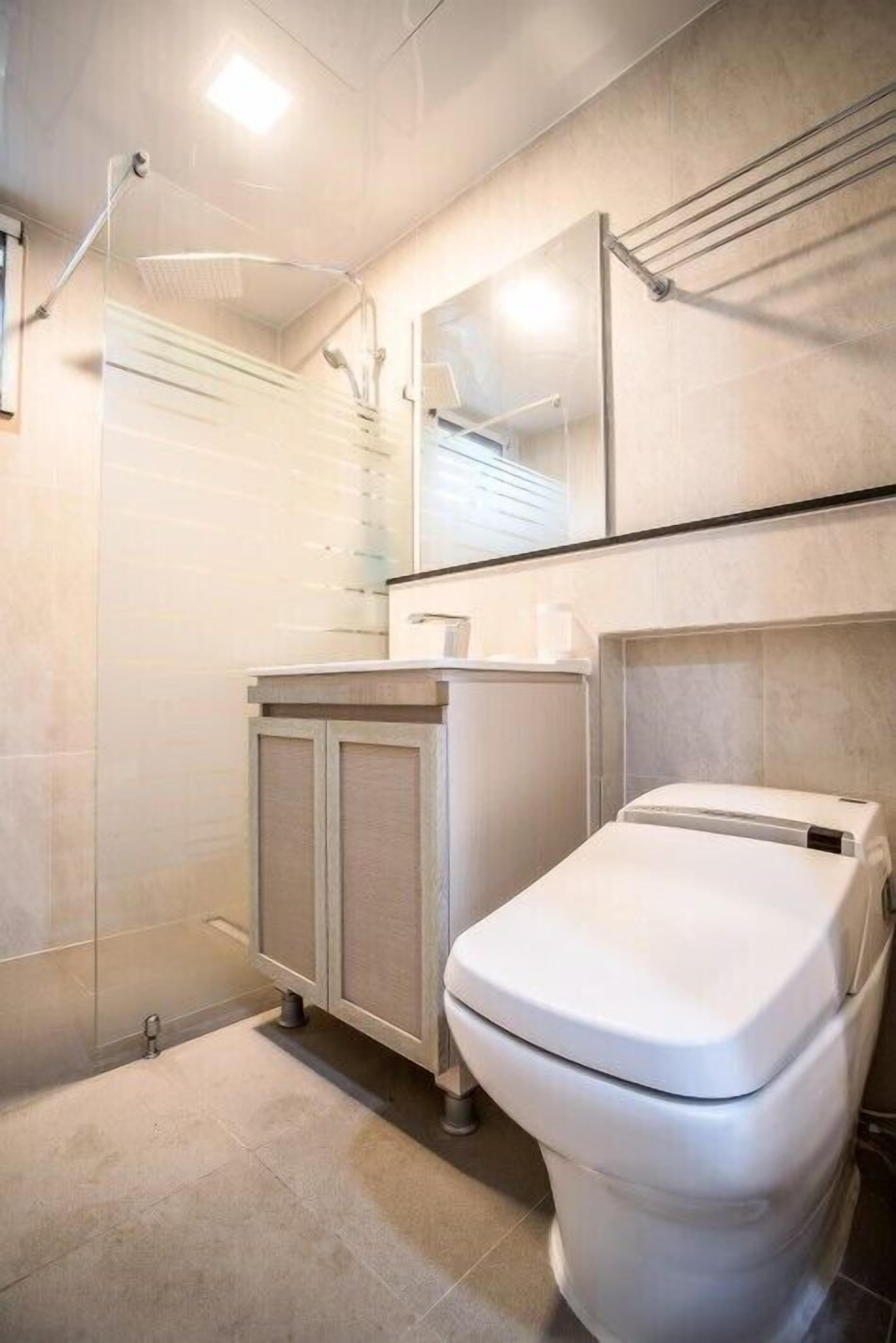 Een moderne badkamer met toilet, douche en wastafel.