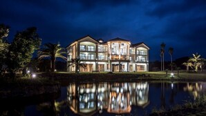A multi-story hotel with a reflective pool in front. - Oakra Resort (Seogwipo)
