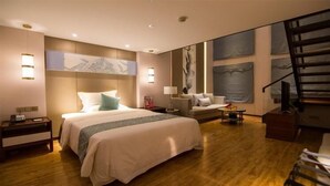 A modern hotel room with a large bed, a sofa, a desk, and a staircase. - Ningxia Dejilinka Hotel (Yinchuan)