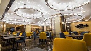 A modern restaurant interior with round ceiling lights, yellow and blue seating, and a marble floor. - Ningxia Dejilinka Hotel (Yinchuan)