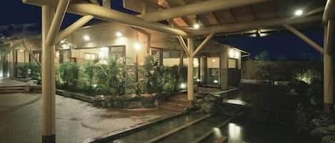 A modern building with a covered outdoor area, stone pathways, and a water feature.