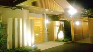 Un edificio moderno con una entrada destacada, techo inclinado y fachada bien iluminada.