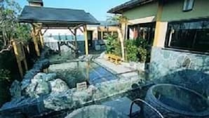 Un área de spa con un jacuzzi, una piscina de piedra y una terraza de madera.
