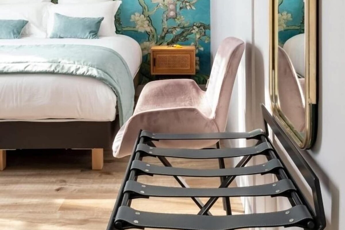 Quarto com cama, uma cadeira, um espelho fixado na parede e um rádio antigo.