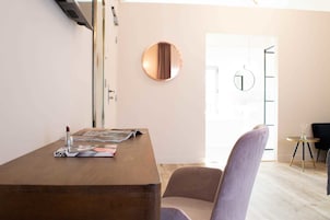 Una habitación moderna con un escritorio de madera, un espejo redondo y una silla.