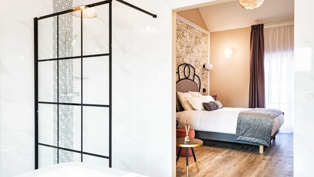 Une chambre à coucher moderne avec un grand lit, une petite table ronde et une salle de bain avec une baignoire.