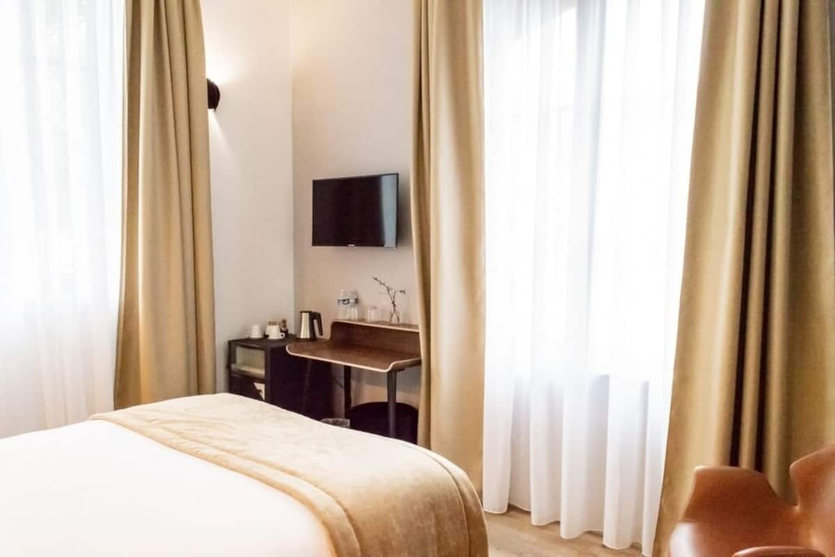 Une chambre d’hôtel avec un lit, un bureau, une télévision et des rideaux.
