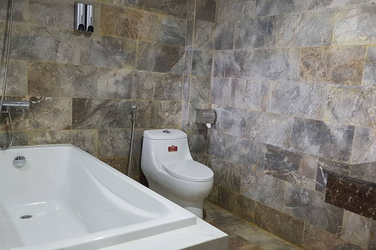 Une salle de bain avec une baignoire, des toilettes et un mur en marbre.