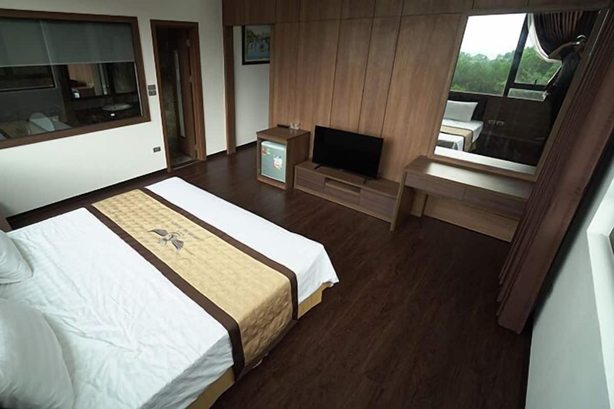 Une chambre d’hôtel avec un lit, une télévision, une petite table et une fenêtre donnant sur un paysage agréable.