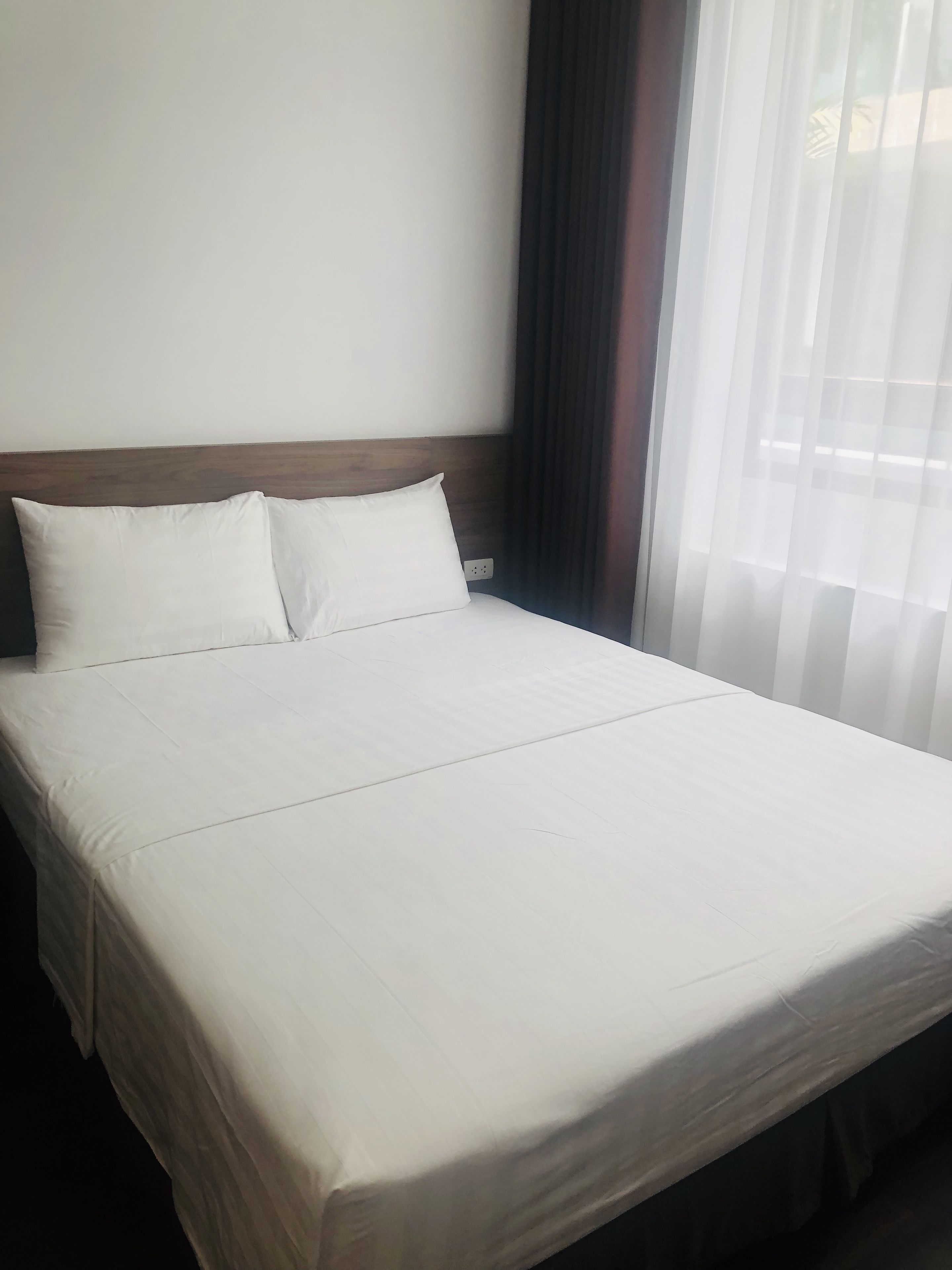 Un lit bien fait, avec du linge de lit blanc, dans une chambre d’hôtel.