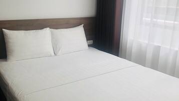 Un lit bien fait, avec du linge de lit blanc, dans une chambre d’hôtel.