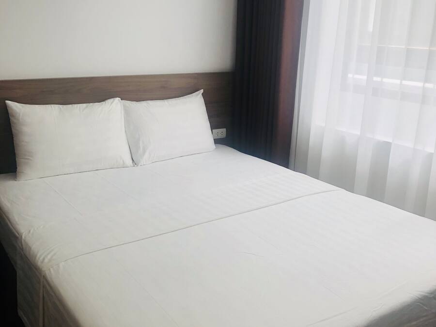 Un lit bien fait, avec du linge de lit blanc, dans une chambre d’hôtel.