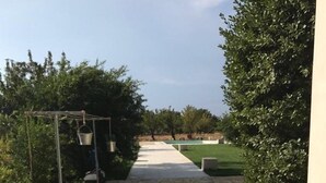 A paved pathway leading to a pool area with a pergola and hanging buckets. - Casa del Grifone (Carovigno)
