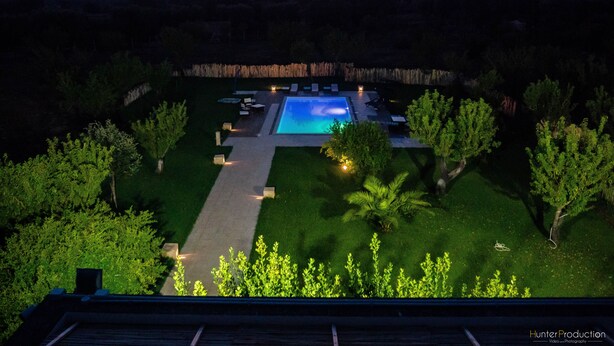 A swimming pool with a surrounding deck, a pathway, and a view of the sunset. - Casa del Grifone (Carovigno)
