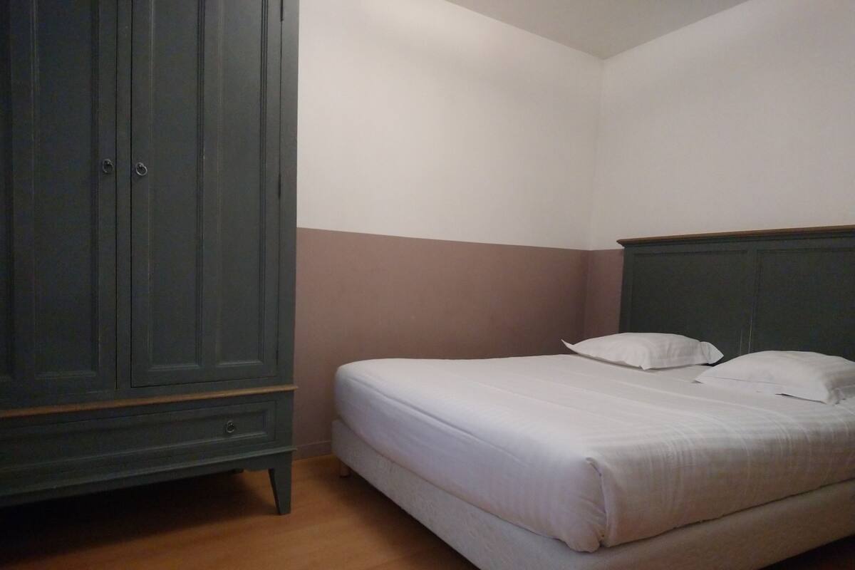 A bedroom with a bed, a wardrobe, and a wooden floor.