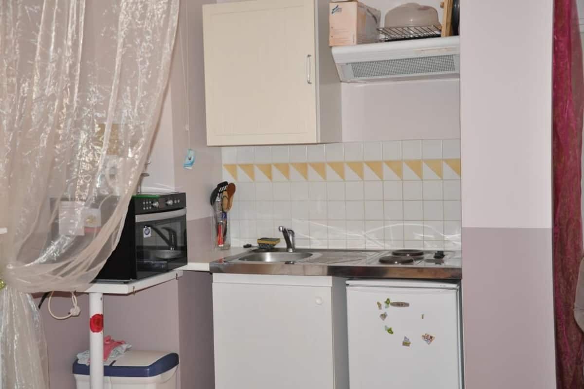 A compact kitchen with a microwave, oven, sink, and a small refrigerator.