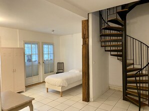 A bedroom with a bed, a desk, a chair, a wardrobe, and a spiral staircase. - Résidences De Chartres (Chartres)
