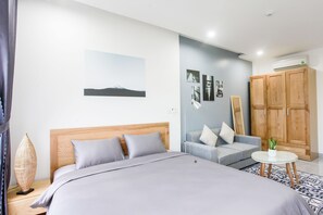 A bedroom with a bed, a sofa, a small table, and a wardrobe. - Carol Apartment (Da Nang)