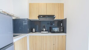 Eine kompakte Küche mit Holzausstattung, einer Mikrowelle, einem Wasserkocher und einem eingebauten Backofen.