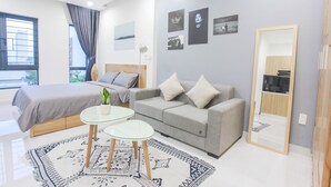 Ein modernes Schlafzimmer mit einem Bett, einem grauen Sofa, einem kleinen Tisch und einem Spiegel.