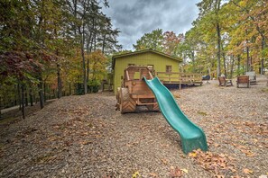 Une aire de jeux avec un toboggan, une cabane en bois et des bancs.