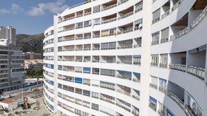 A multi-story hotel with balconies, a parking area, and a mountainous backdrop. - PRADO, A-7º-72 PK INT 83 (Cullera)