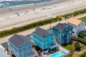 Une propriété située en bord de mer, comprenant plusieurs bâtiments, une piscine et une plage en arrière-plan.