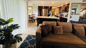 A modern living room with a brown sofa, a dining area with chairs, and a kitchen with dark cabinets and stainless steel appliances. - Home away from Home.Family & Pet friendly30+days (Canyon Lake)