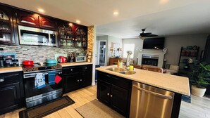 A modern kitchen with dark cabinetry, stainless steel appliances, and a central island with a sink. - Home away from Home.Family & Pet friendly30+days (Canyon Lake)
