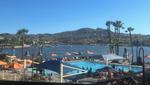 A pool area with umbrellas, palm trees, and a mountainous backdrop. - Home away from Home.Family & Pet friendly30+days (Canyon Lake)