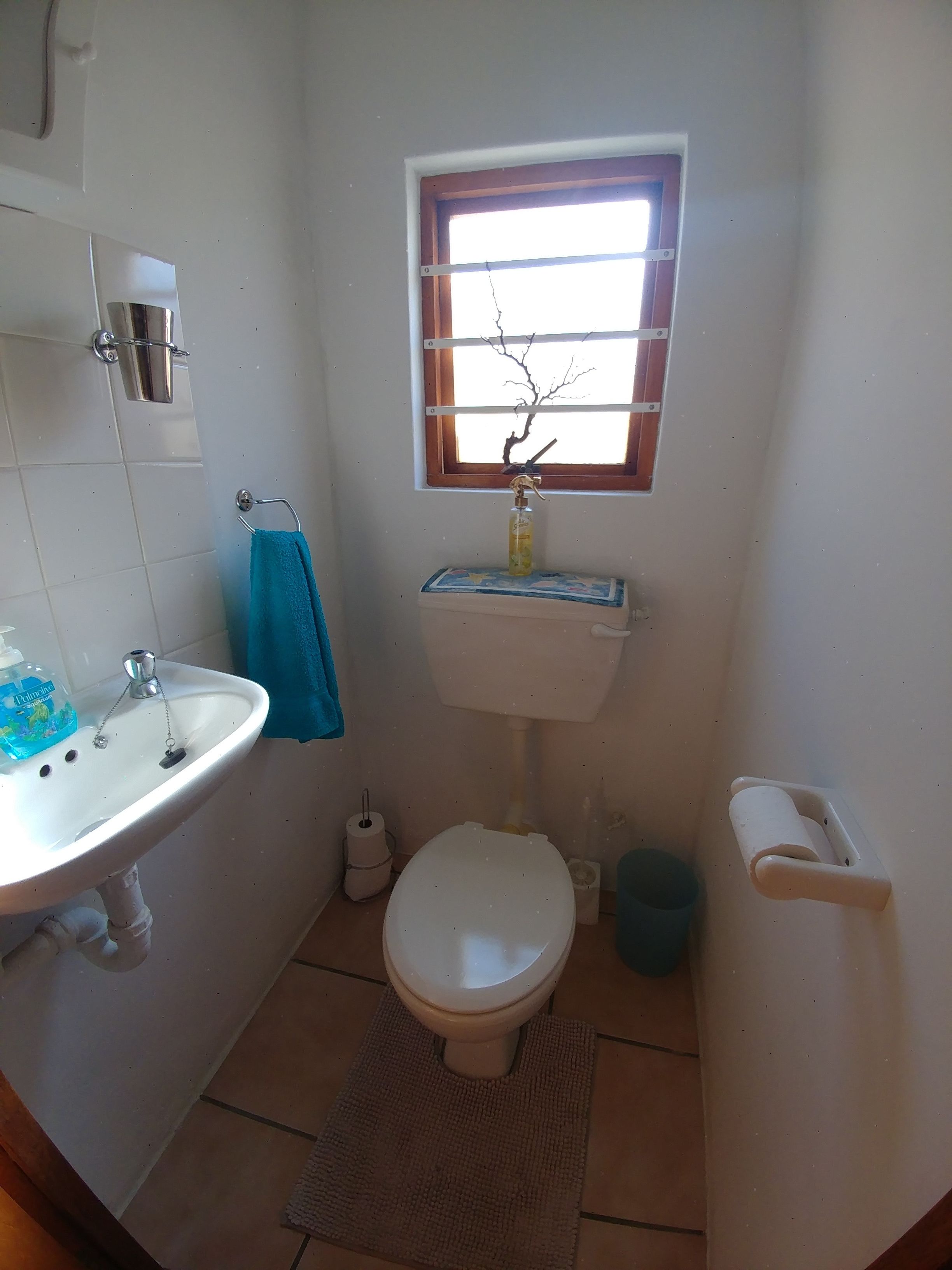 A small bathroom with a white sink, toilet, and window.