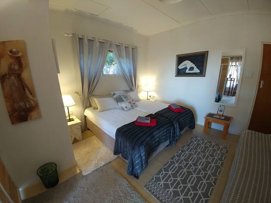 A bedroom with a bed, two bedside tables, a nightstand, a mirror, a painting, and a rug.