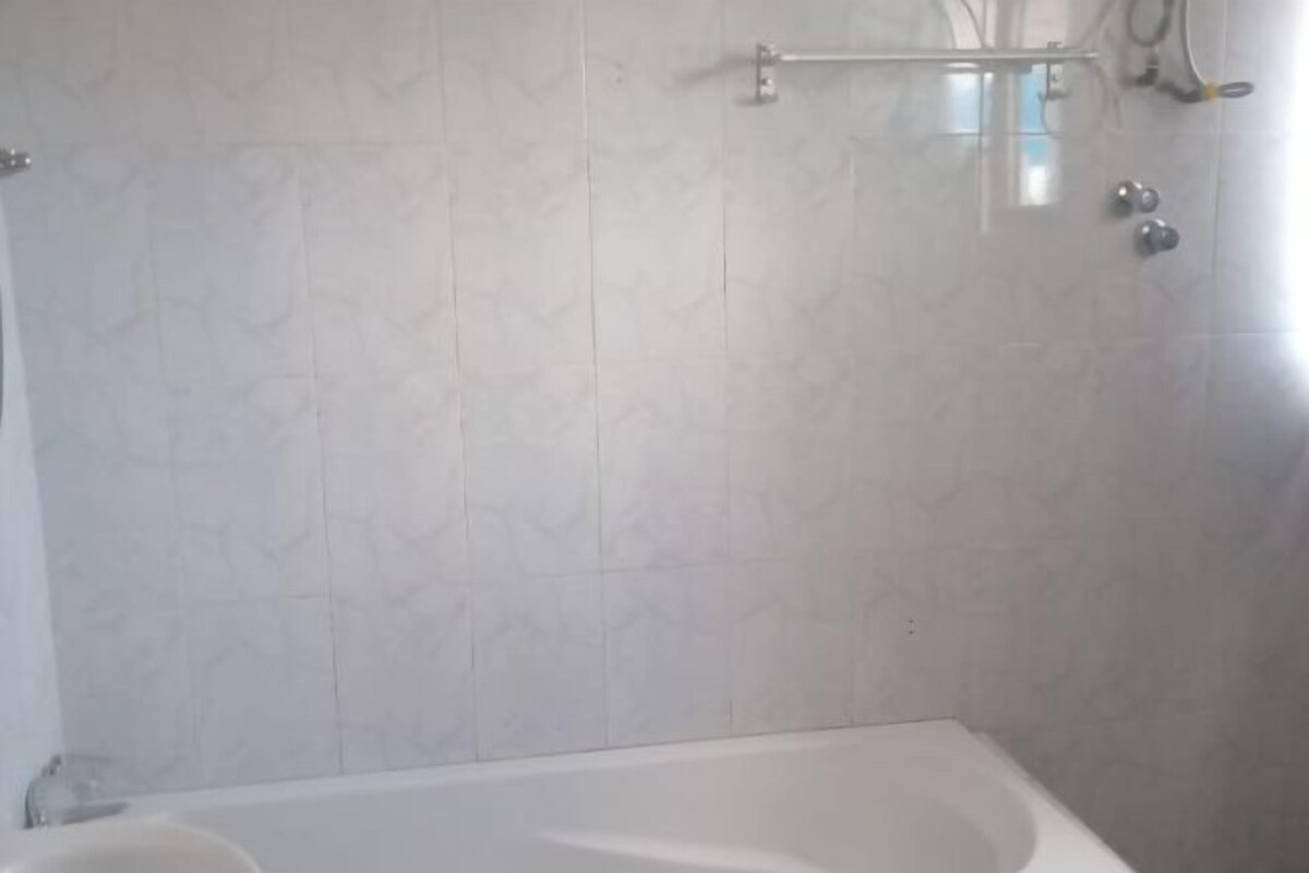 A bathroom with a bathtub, tiled walls, and a towel rack.