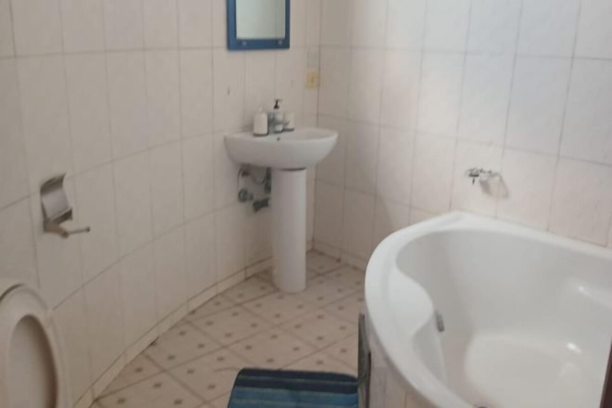 A bathroom with a white sink, a mirror, a toilet, and a bathtub.